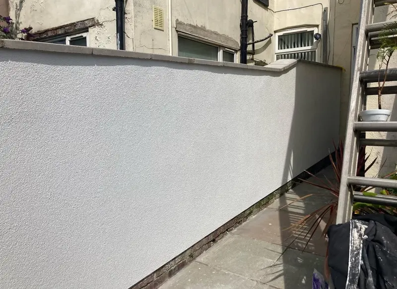 Garden wall after rendering, with a smooth white finish
