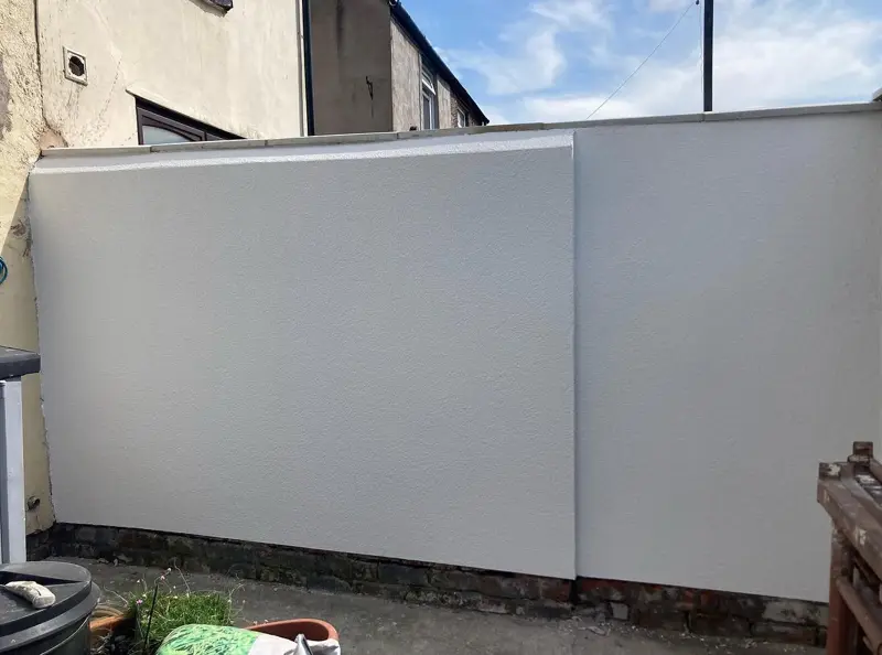 Garden wall after rendering, with a smooth white finish